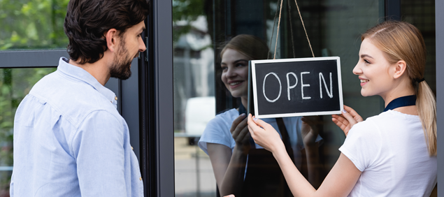 woman showing open sign on small business